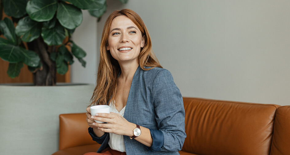 A woman sat with a cup in her hands smiling